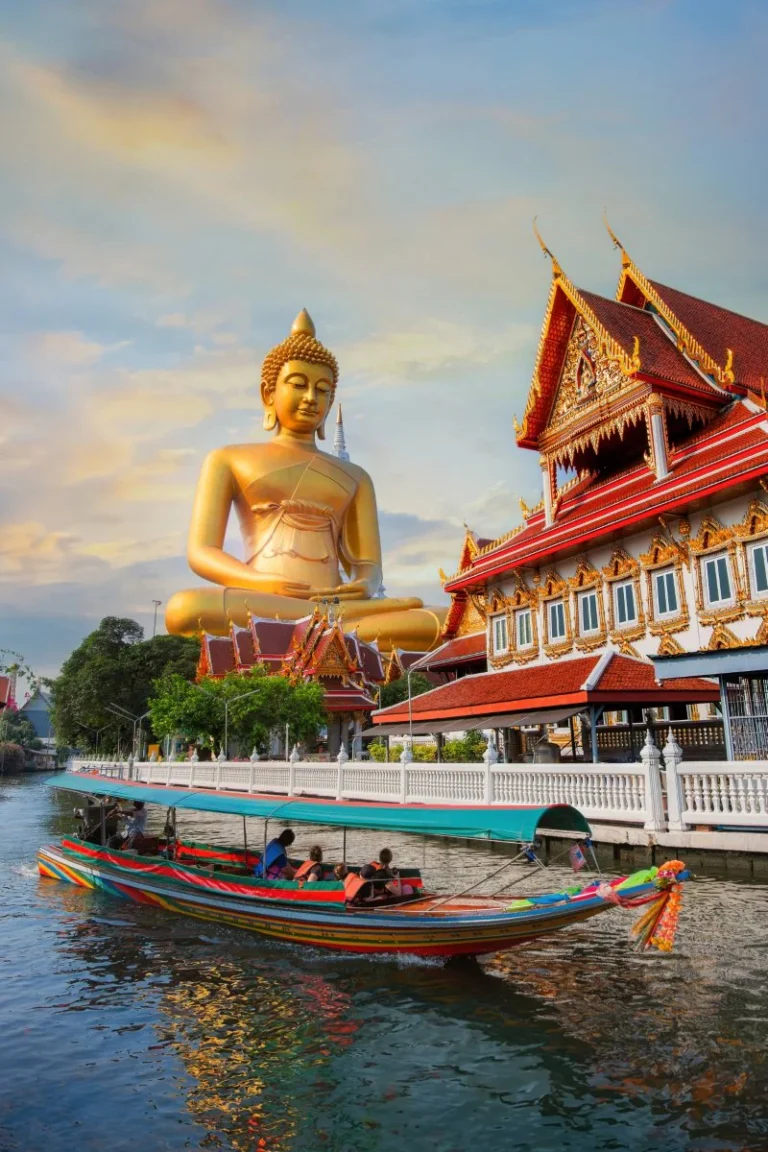 Traditional Thai longtail boat passing the giant golden Buddha at Wat Paknam Phasi Charoen in Bangkok.